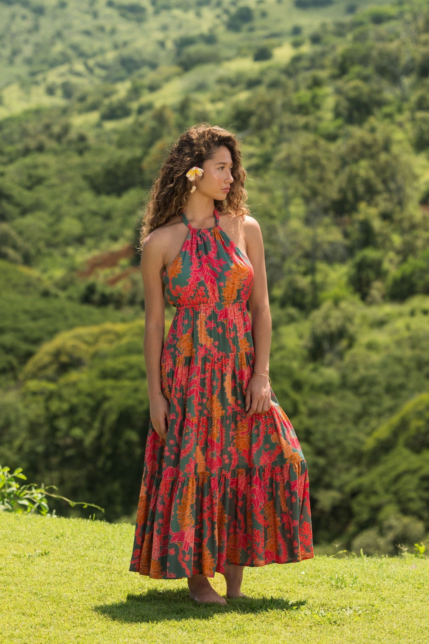 woman with brown hair wearing a colorful flowy maxi dress with tropical lei print