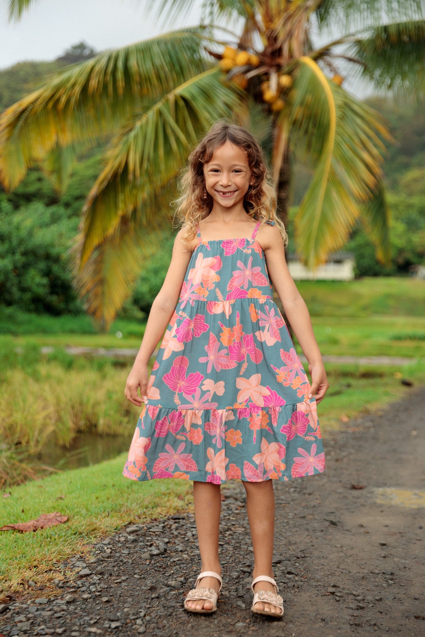little girl wearing long teal dress with tie sleeve and floral pattern