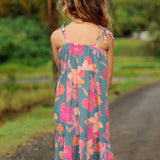 little girl wearing long teal dress with tie sleeve and floral pattern