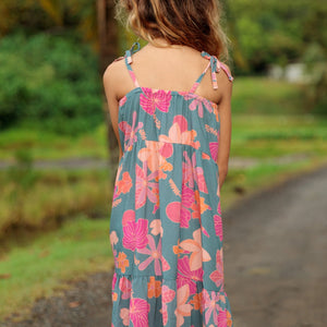 little girl wearing long teal dress with tie sleeve and floral pattern
