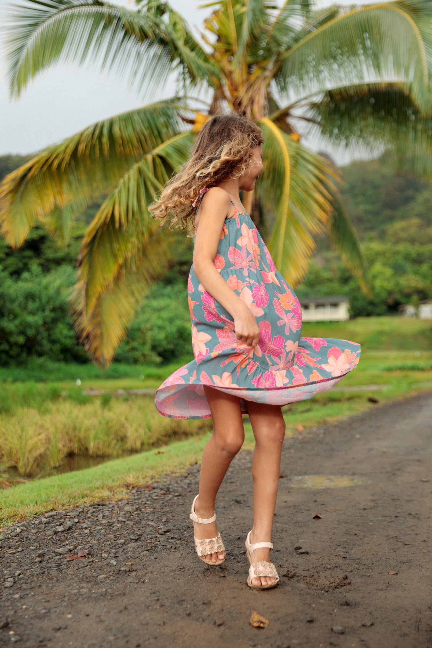 little girl wearing long teal dress with tie sleeve and floral pattern