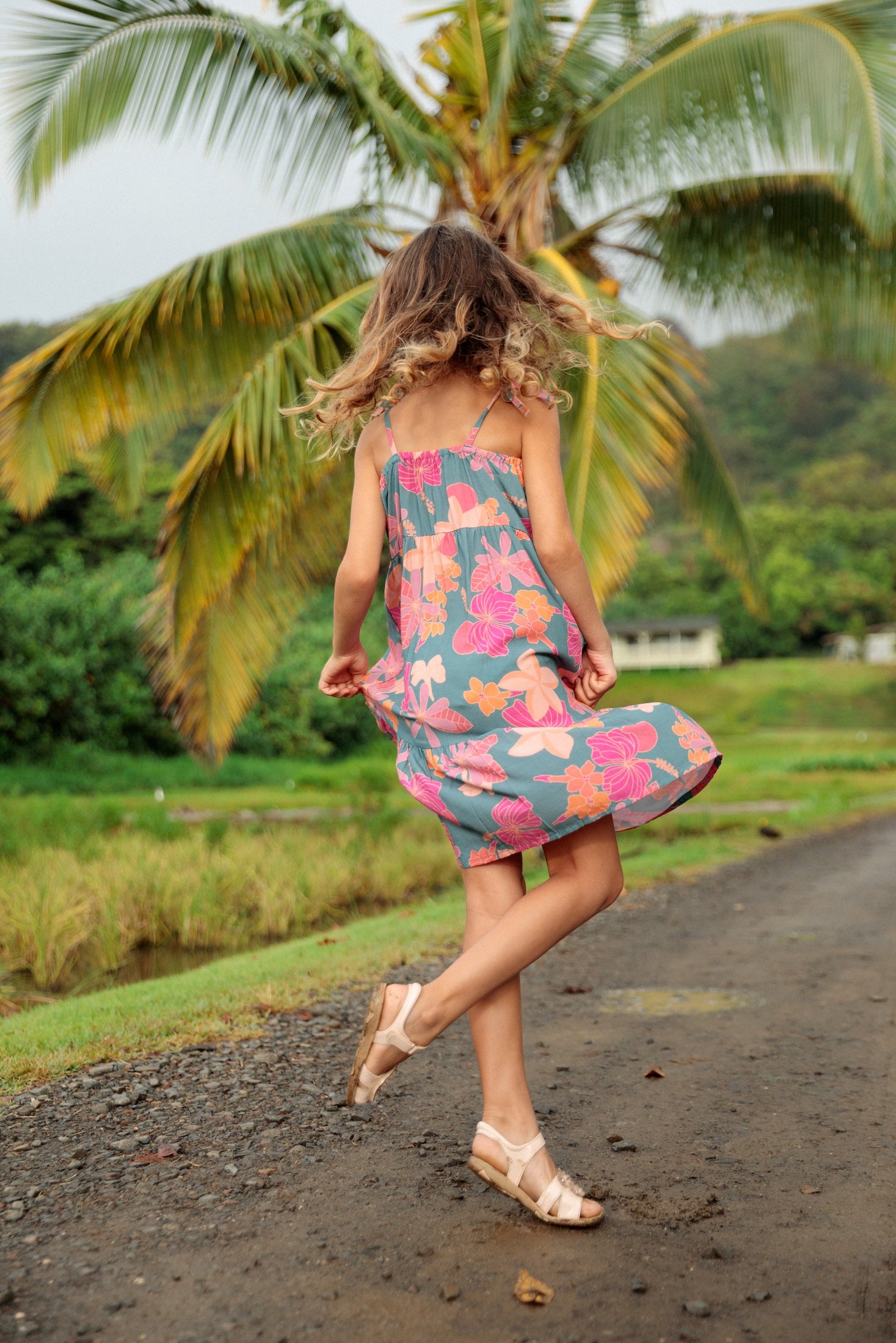 little girl wearing long teal dress with tie sleeve and floral pattern