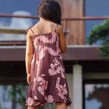 little girl wearing a long brown dress with tie sleeve with light pink lei awapuhi print