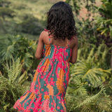 girl with brown hair wearing a colorful dress with tropical lei print