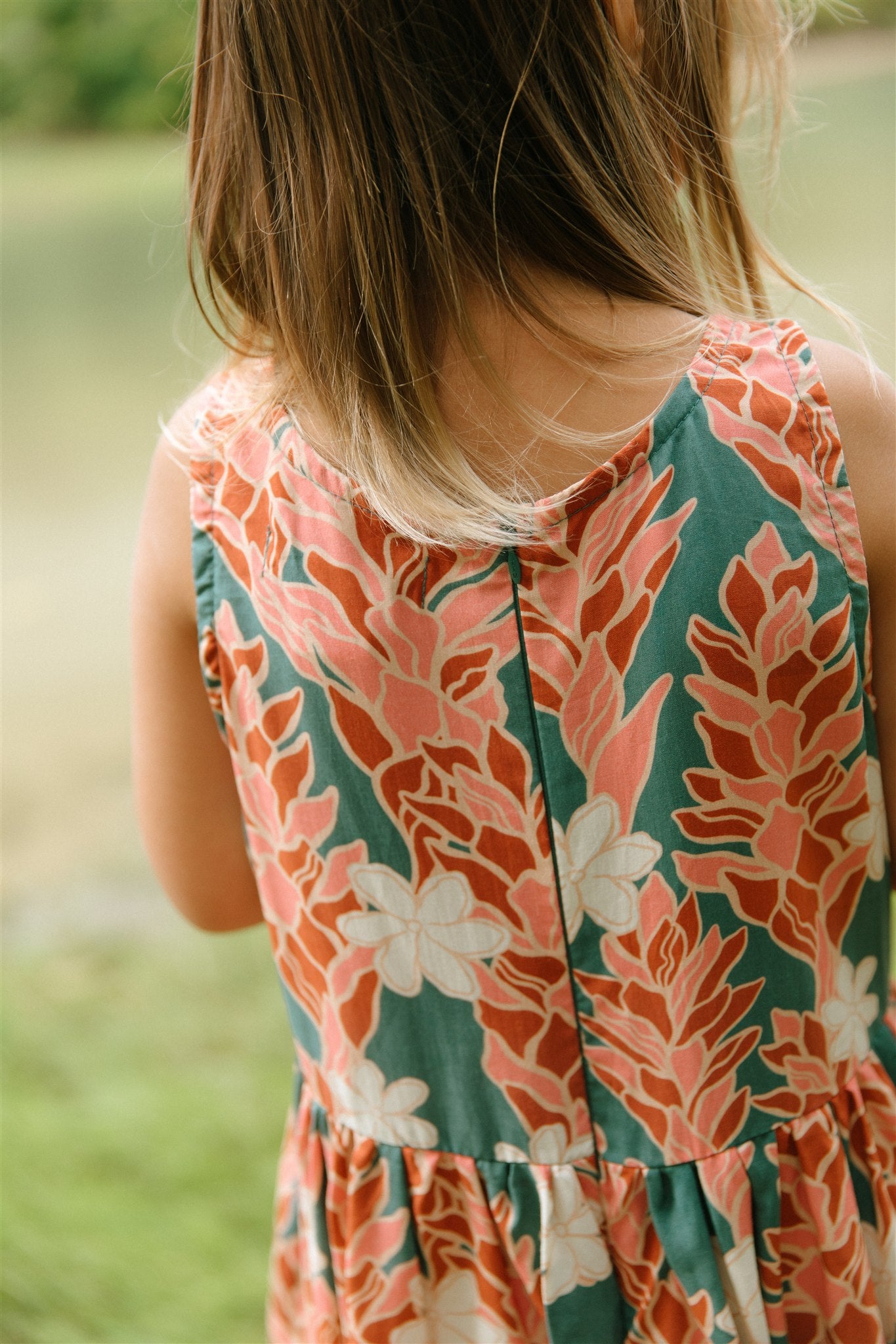 little girl wearing a knee length dress with red ginger and tiare print