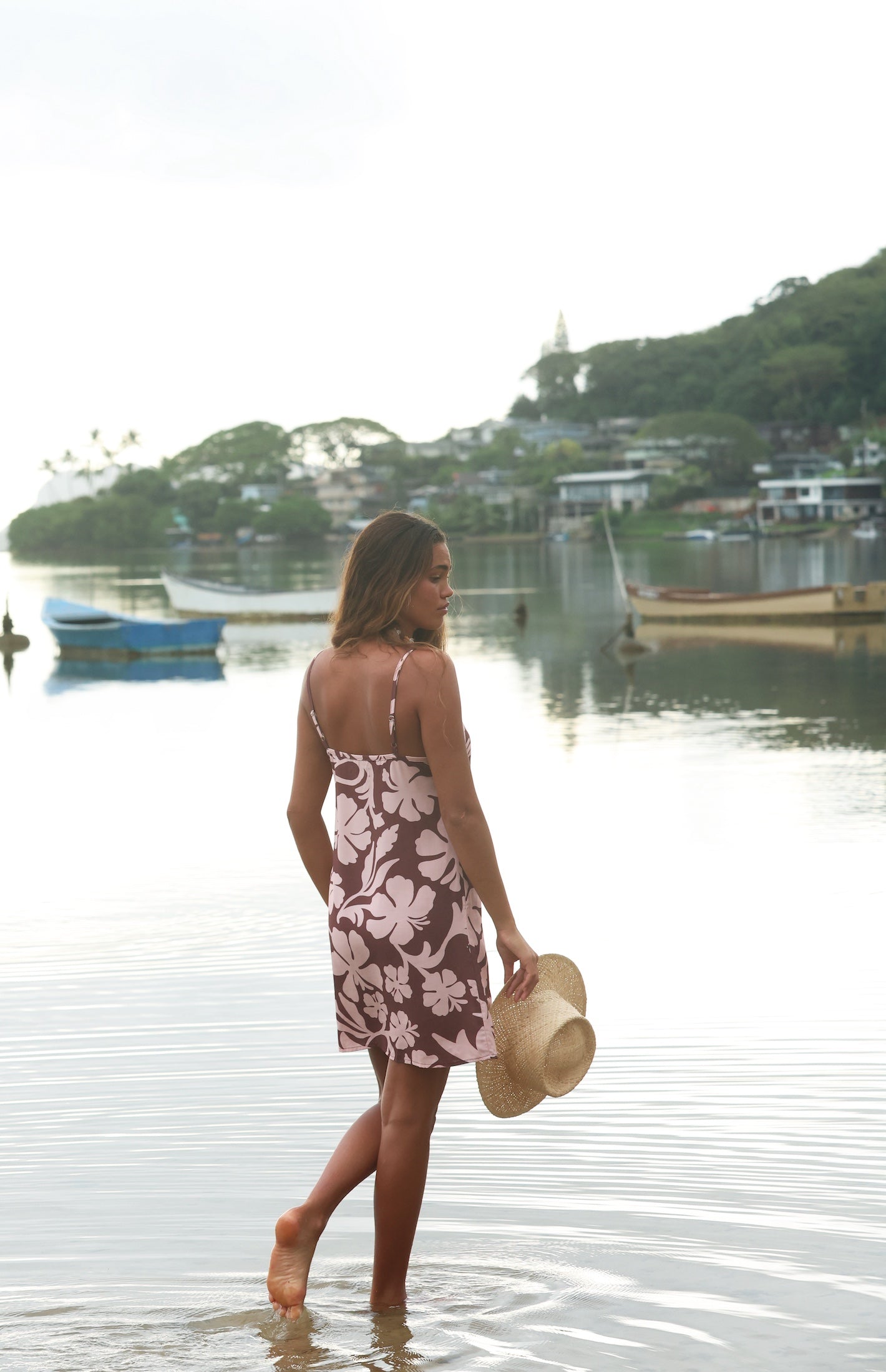 Woman with brown hair wearing a simple slip dress with scoop neck in blush and brown hibiscus print