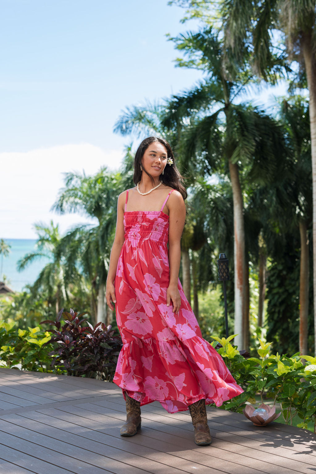 Woman wearing red sleeveless maxi dress with large pink floral print.