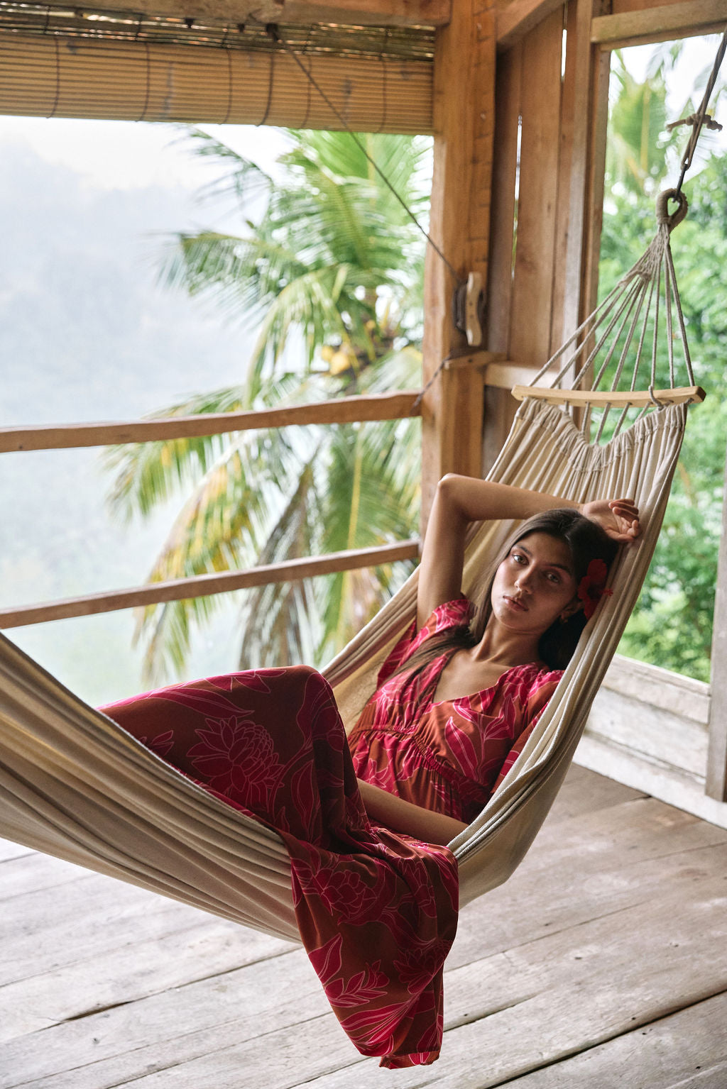 Woman with dark hair wearing tiered maxi dress with sleeves. It is the Mariana Dress in the Garden 'Awapuhi print.