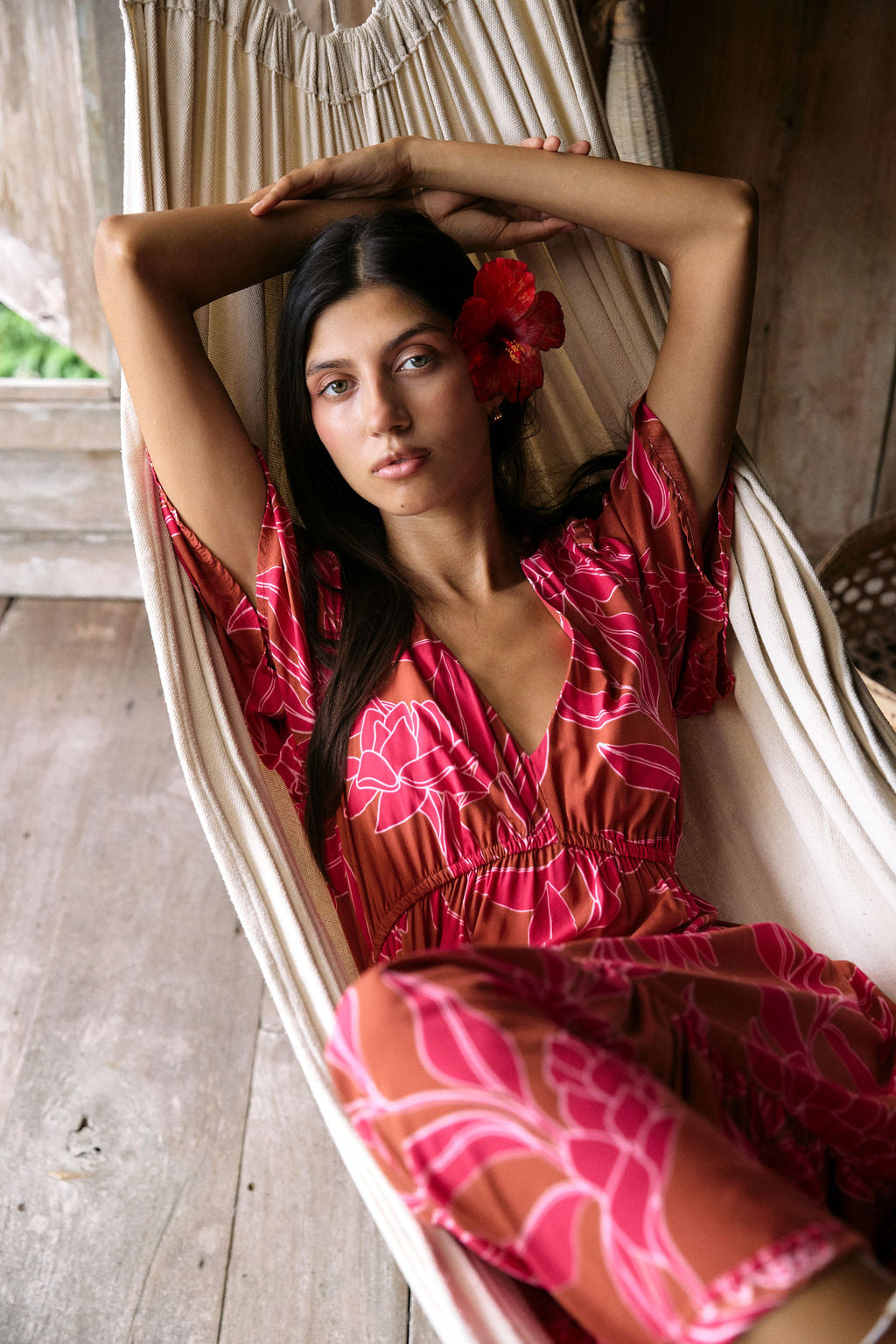 Woman with dark hair wearing tiered maxi dress with sleeves. It is the Mariana Dress in the Garden 'Awapuhi print.