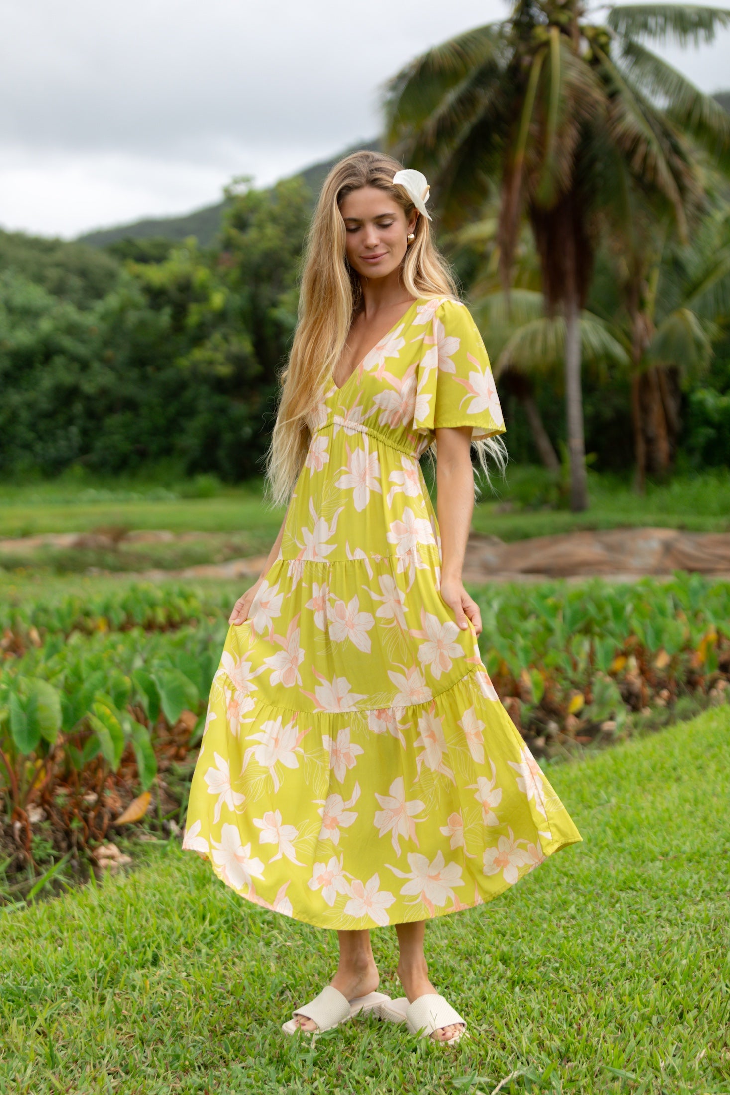 woman wearing a bright green v neck maxi dress with flutter sleeves with orchid print