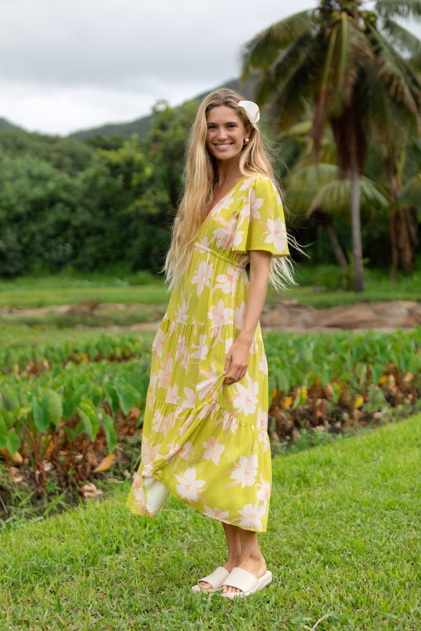 woman wearing a bright green v neck maxi dress with flutter sleeves with orchid print