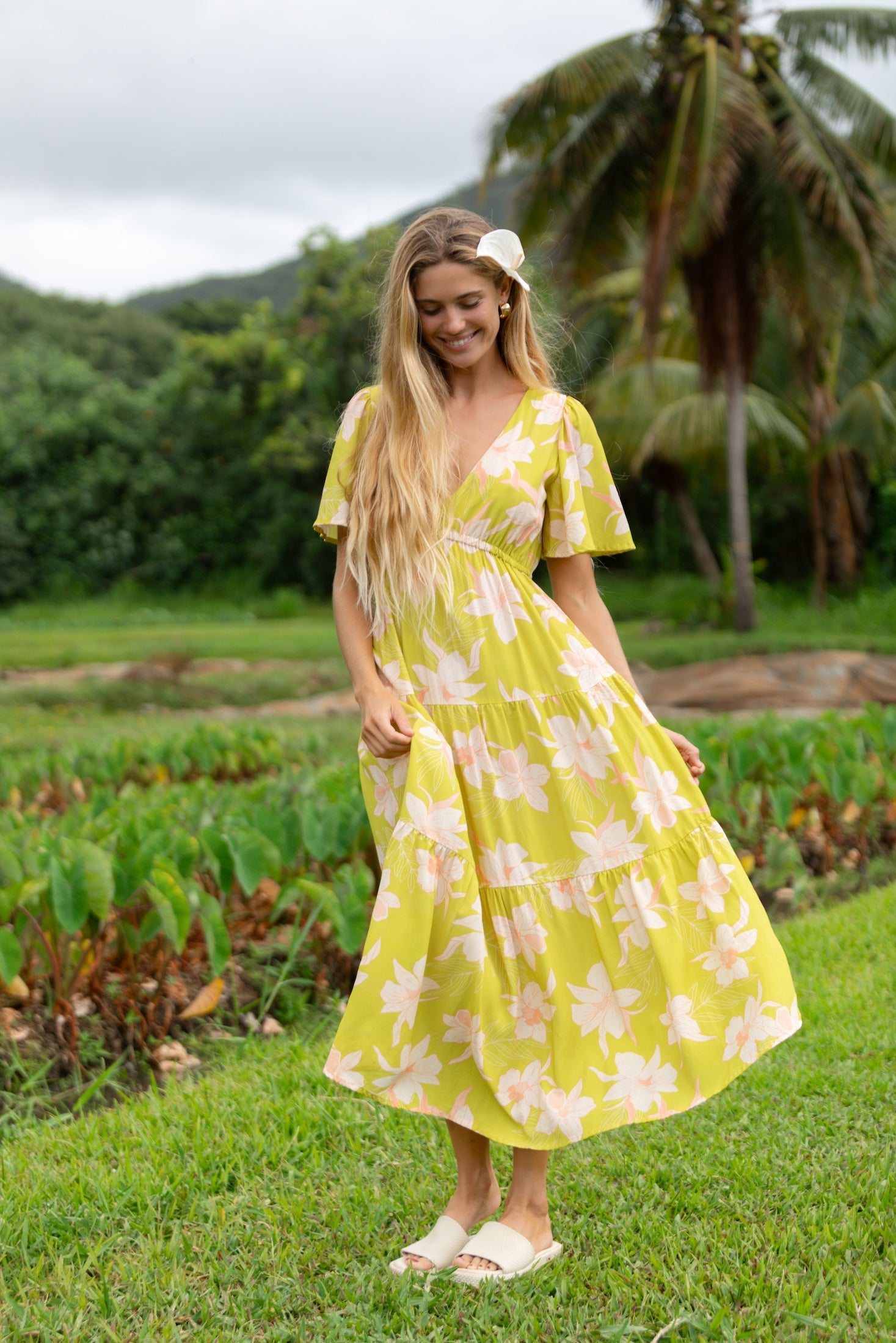woman wearing a bright green v neck maxi dress with flutter sleeves with orchid print