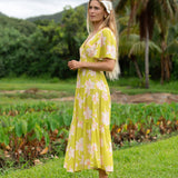 woman wearing a bright green v neck maxi dress with flutter sleeves with orchid print