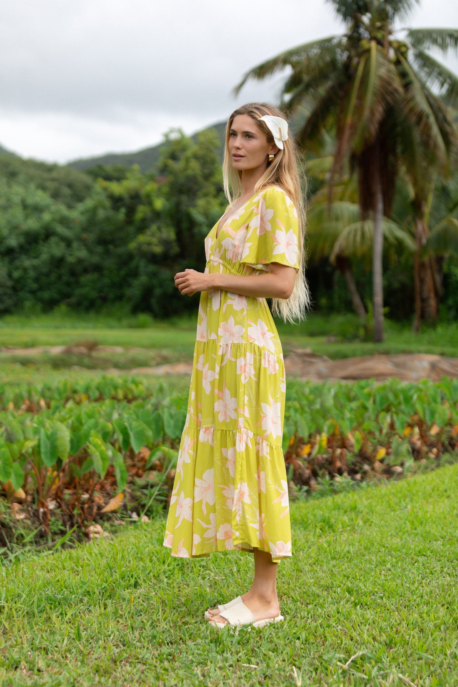 woman wearing a bright green v neck maxi dress with flutter sleeves with orchid print