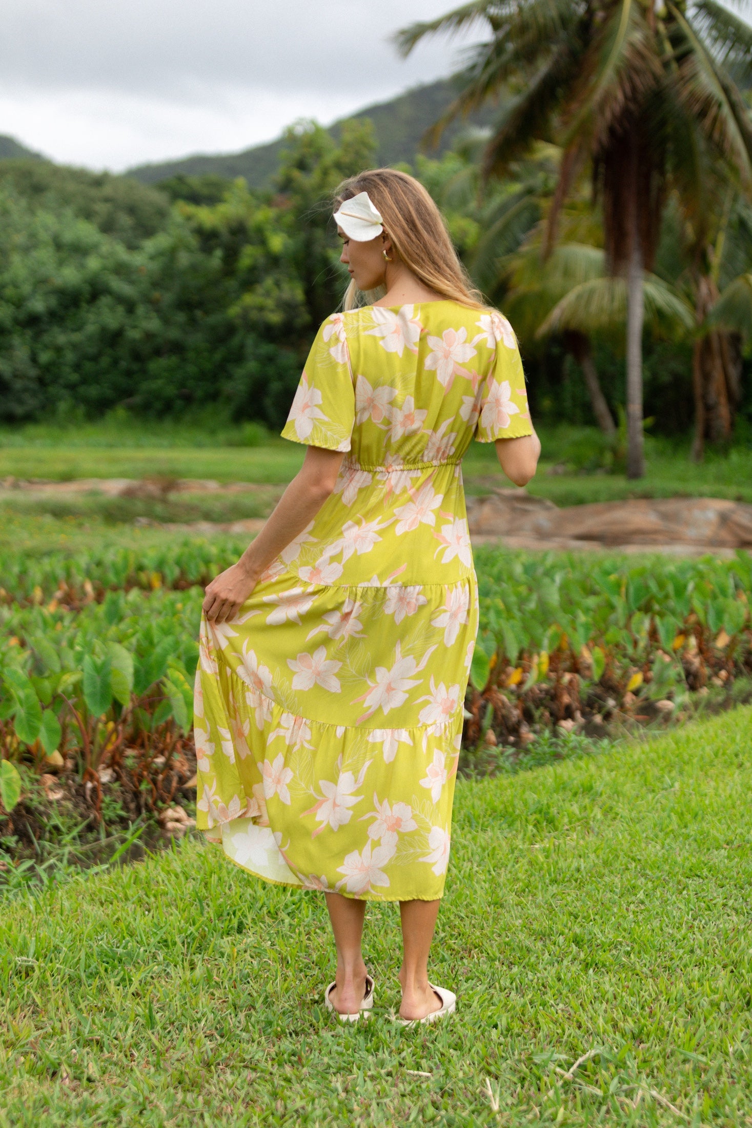 woman wearing a bright green v neck maxi dress with flutter sleeves with orchid print