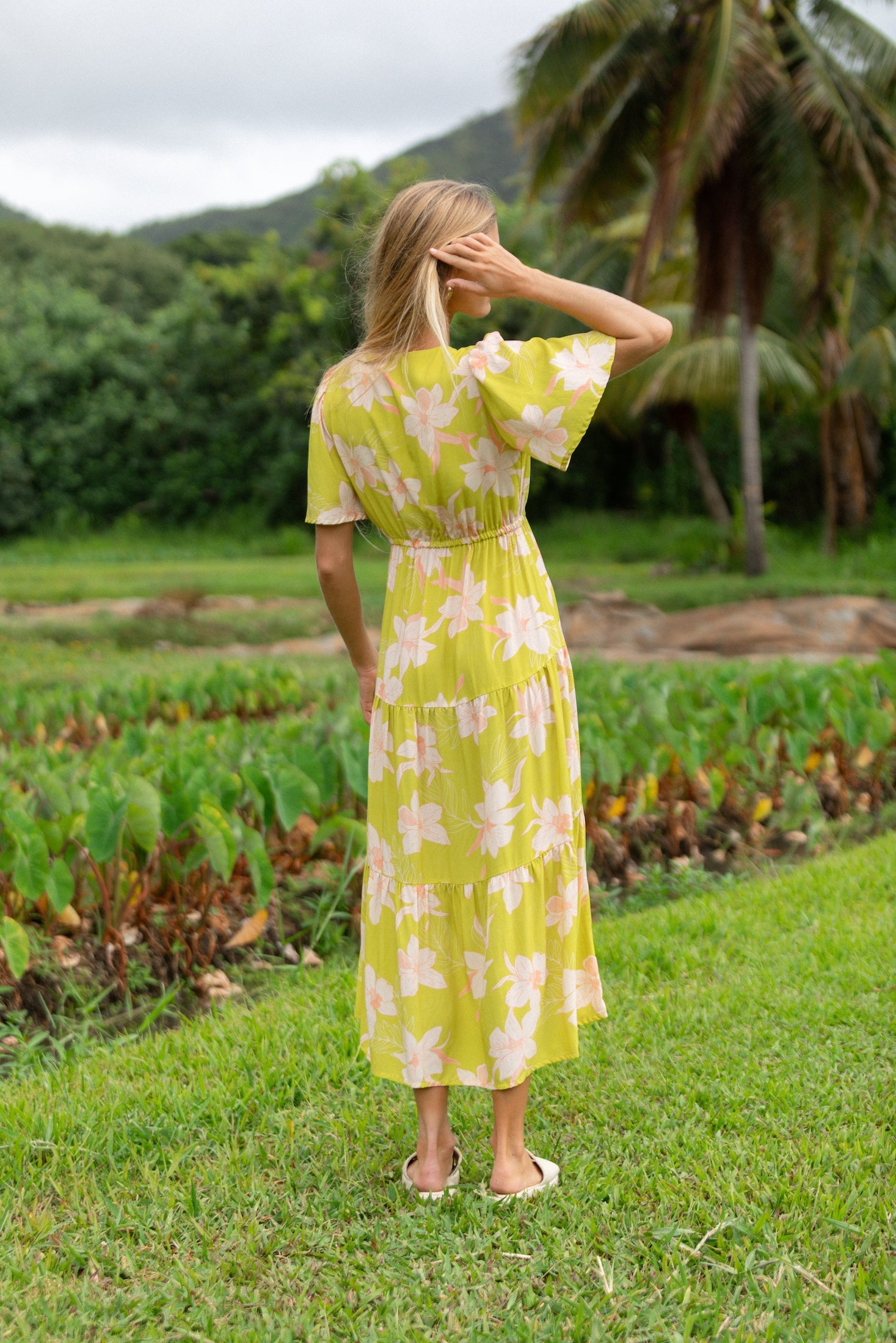 woman wearing a bright green v neck maxi dress with flutter sleeves with orchid print
