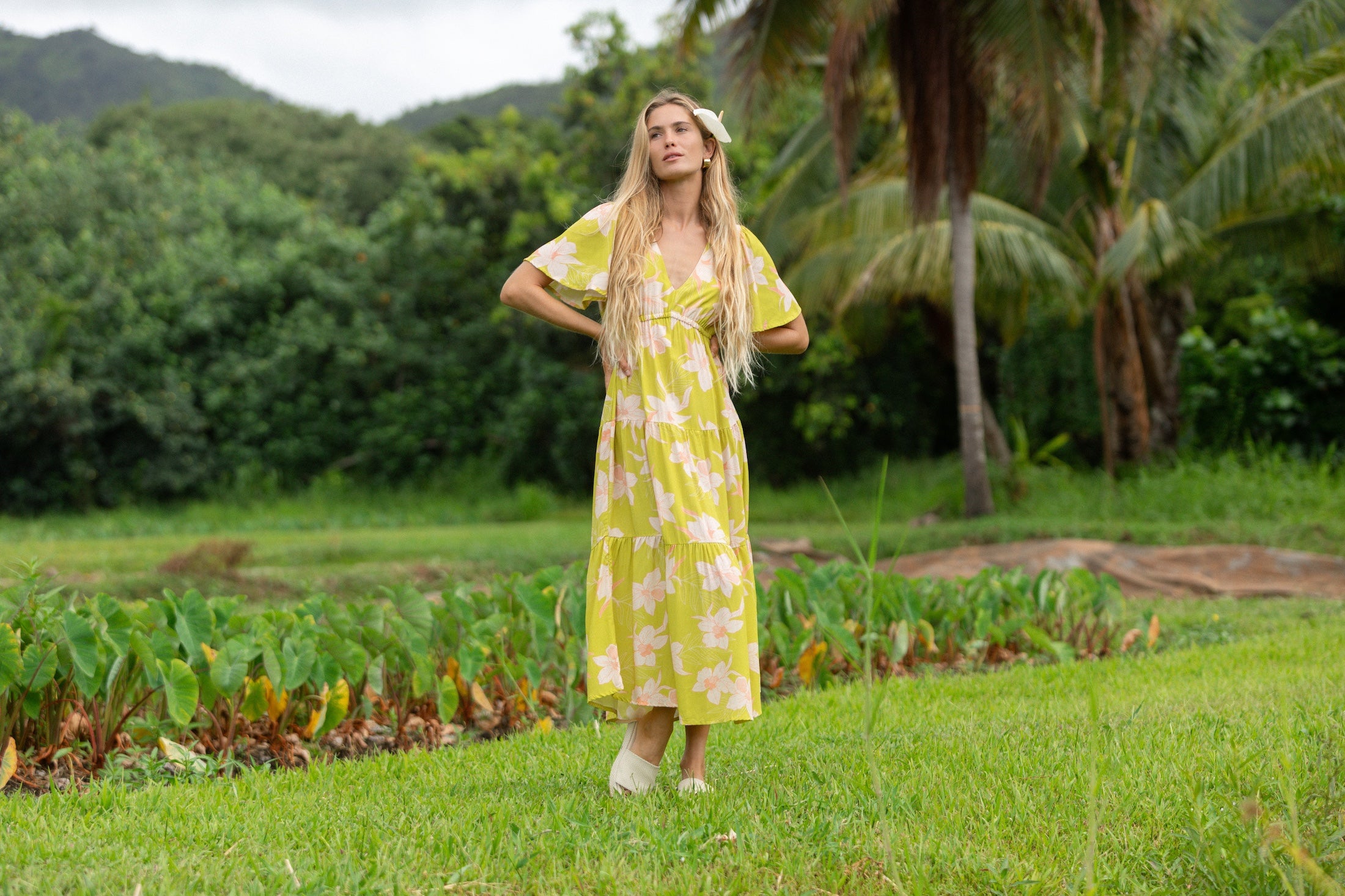 woman wearing a bright green v neck maxi dress with flutter sleeves with orchid print