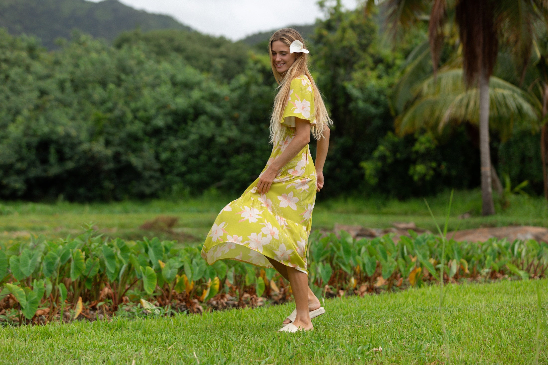 woman wearing a bright green v neck maxi dress with flutter sleeves with orchid print