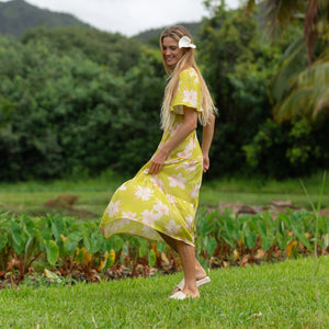 woman wearing a bright green v neck maxi dress with flutter sleeves with orchid print