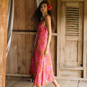A woman with dark hair wears a YIREH full length dress featuring a knotted, sweetheart neckline. It is the Marina Dress in the Garden 'Awapuhi print.