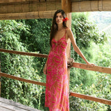 A woman with dark hair wears a YIREH full length dress featuring a knotted, sweetheart neckline. It is the Marina Dress in the Garden 'Awapuhi print.