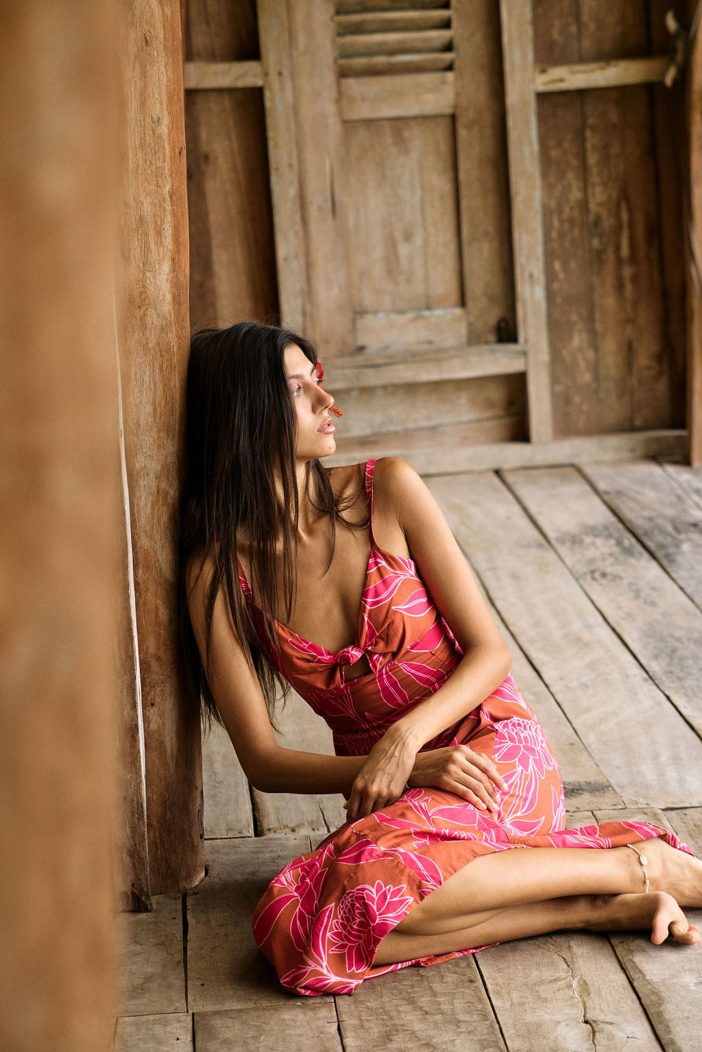 A woman with dark hair wears a YIREH full length dress featuring a knotted, sweetheart neckline. It is the Marina Dress in the Garden 'Awapuhi print.
