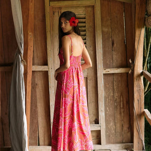 A woman with dark hair wears a YIREH full length dress featuring a knotted, sweetheart neckline. It is the Marina Dress in the Garden 'Awapuhi print.
