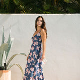 woman with black hair wearing a maxi dress with knot cutout neckline in a navy and pink hibiscus print.