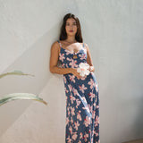 woman with black hair wearing a maxi dress with knot cutout neckline in a navy and pink hibiscus print.