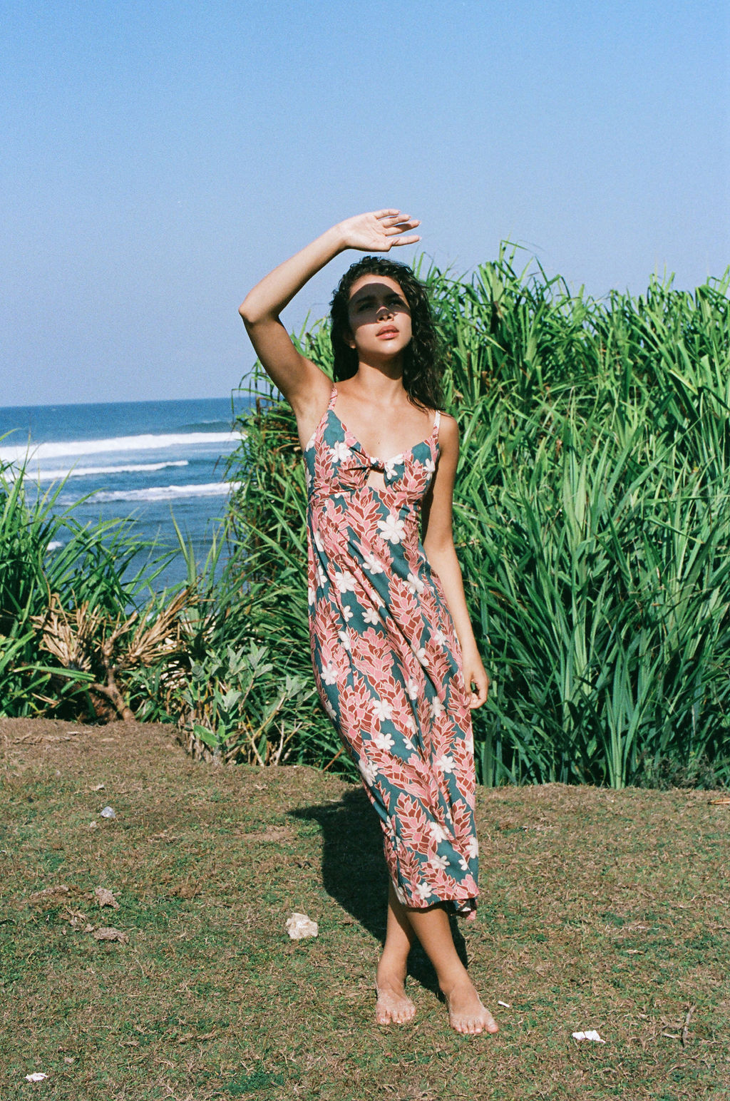 woman with brown hair wearing wearing a long maxi dress with knot tie neckline in a red ginger and tiare print