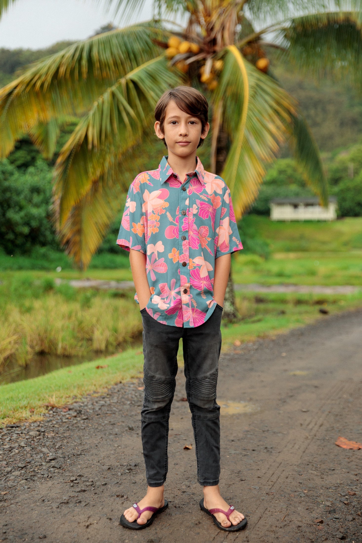 little boy wearing a teal button up aloha shirt with floral pattern