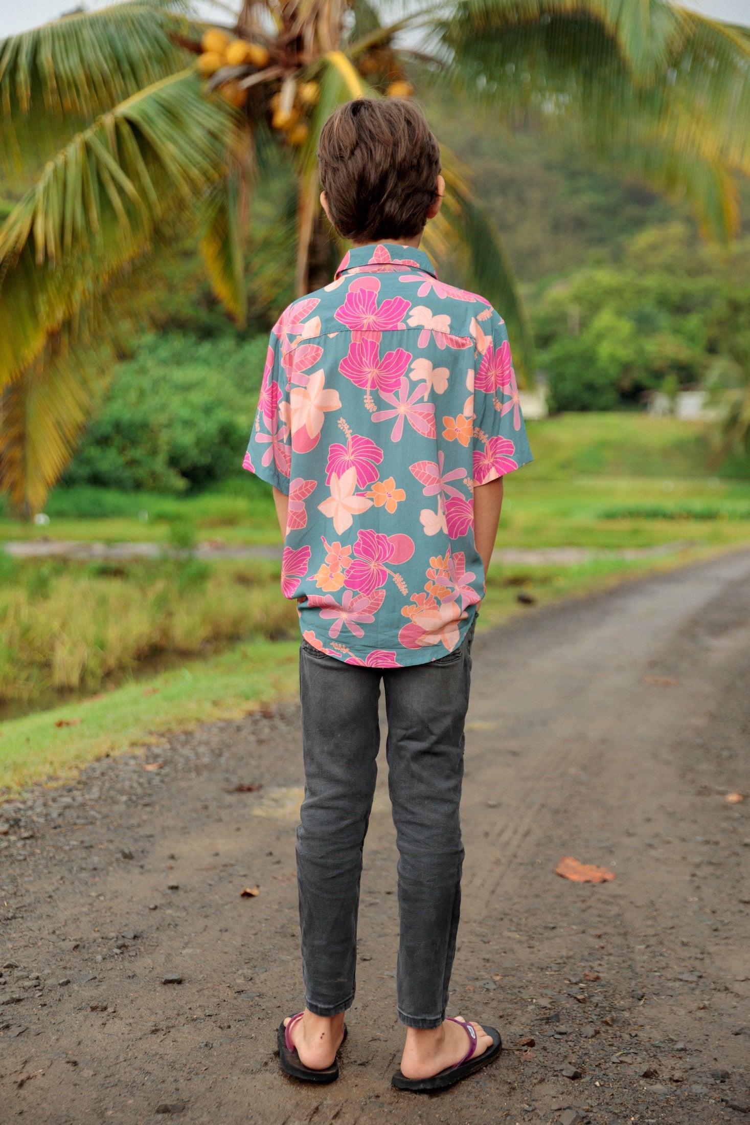 little boy wearing a teal button up aloha shirt with floral pattern