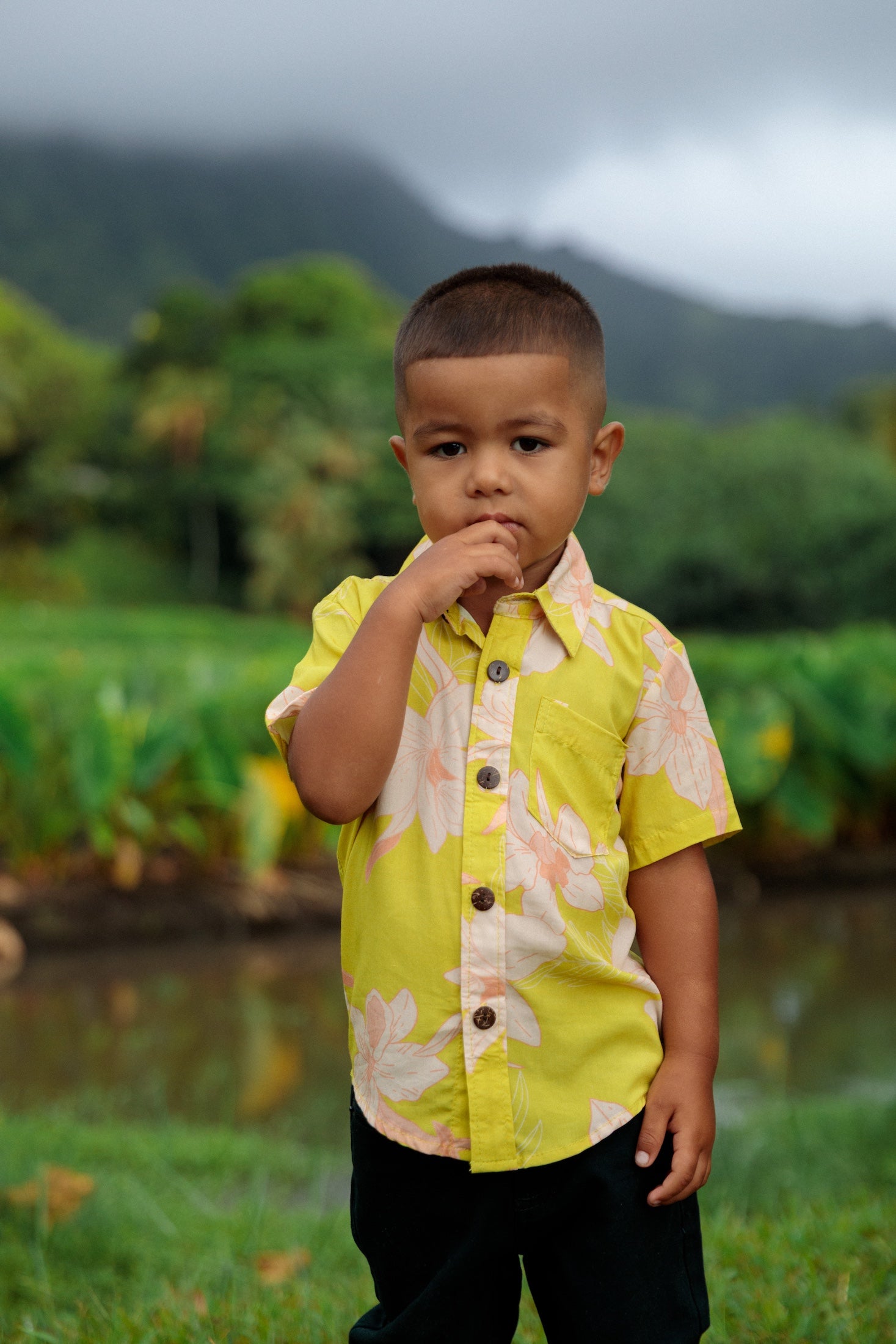 little boy wearing bright green aloha shirt with orchid print