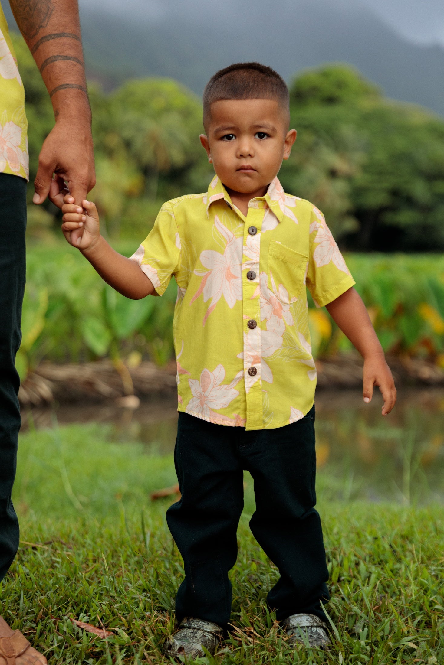 little boy wearing bright green aloha shirt with orchid print