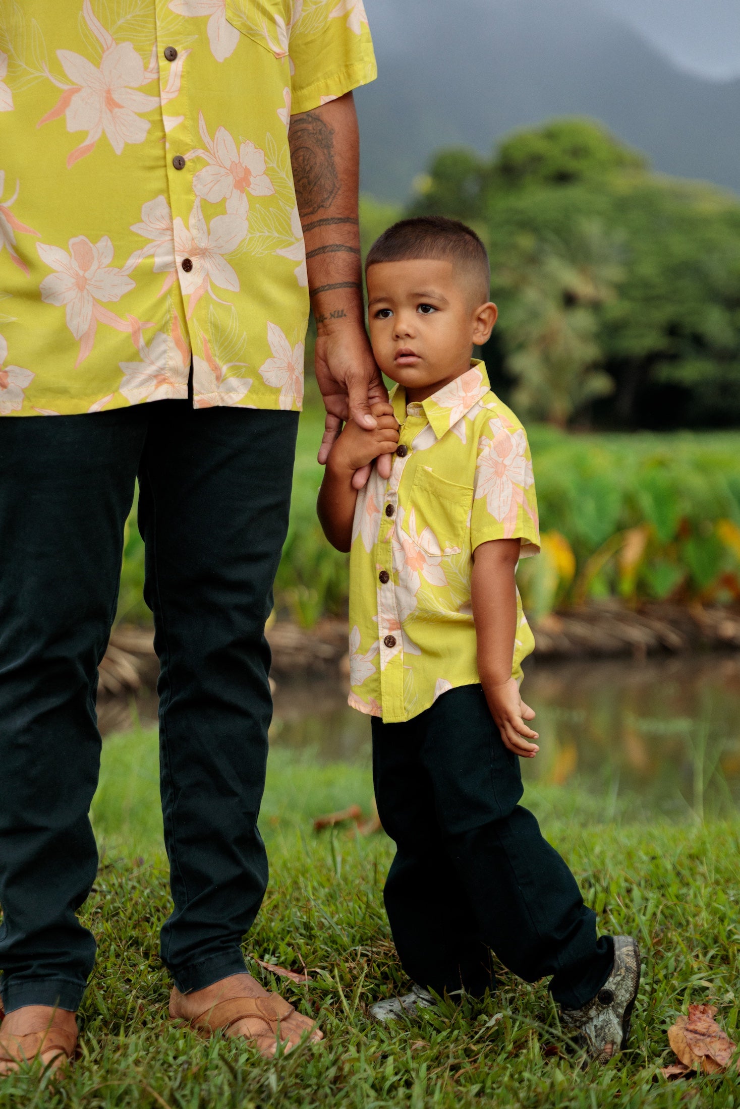 little boy wearing bright green aloha shirt with orchid print