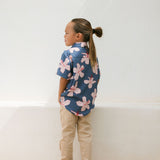 little boy wearing button up aloha shirt in navy and pink hibiscus print.