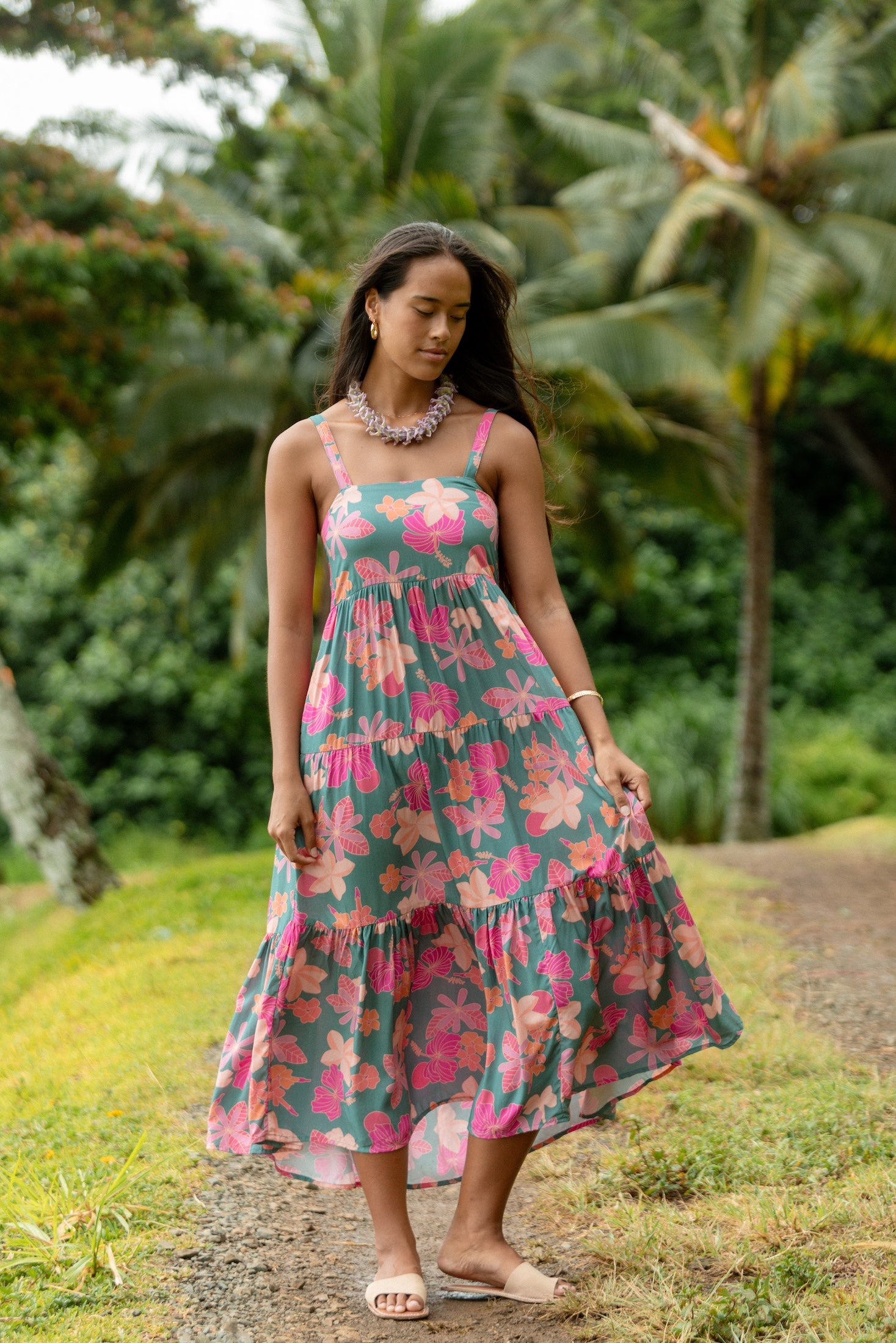 woman with brown hair wearing a teal maxi dress with orange and pink floral print