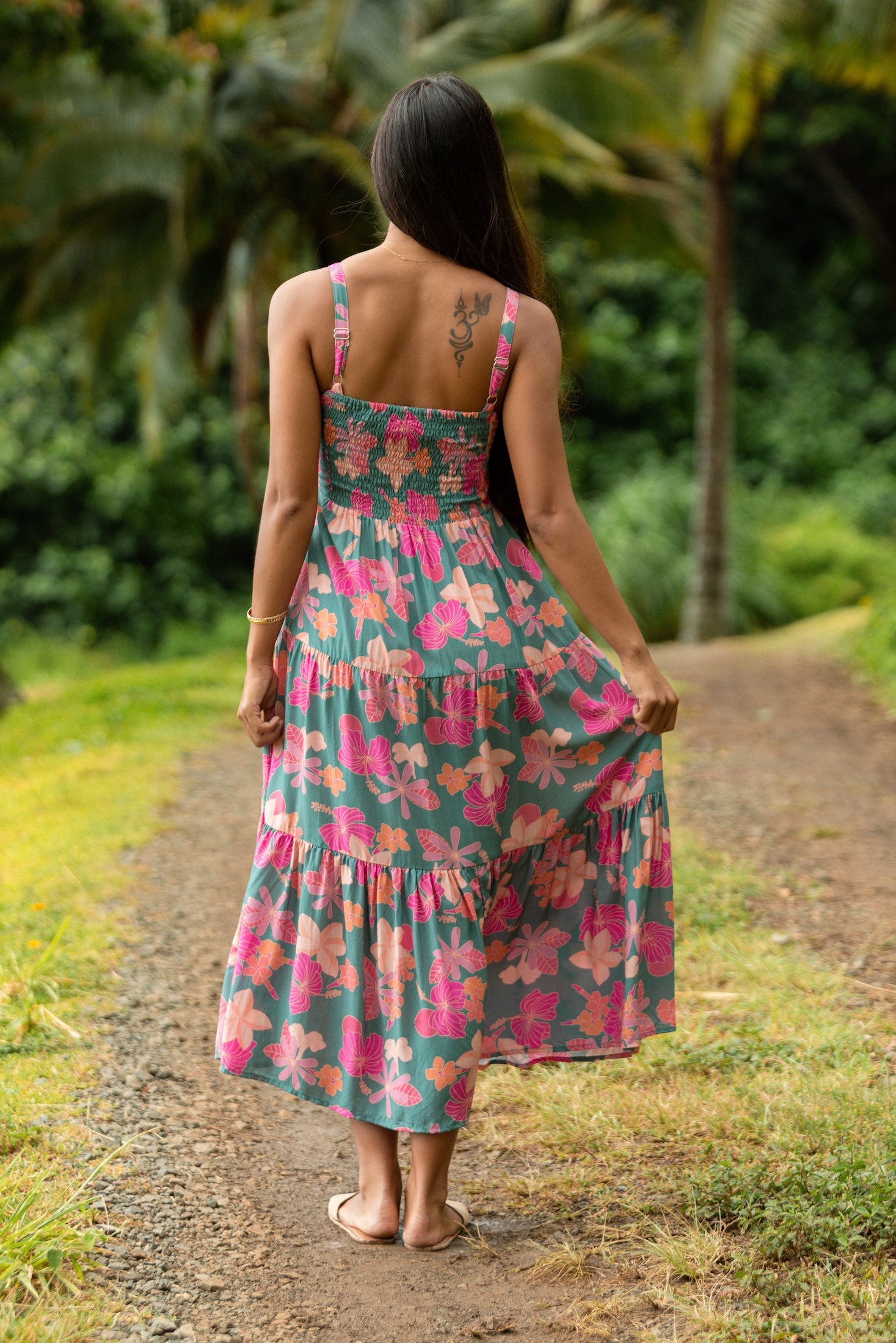 woman with brown hair wearing a teal maxi dress with orange and pink floral print