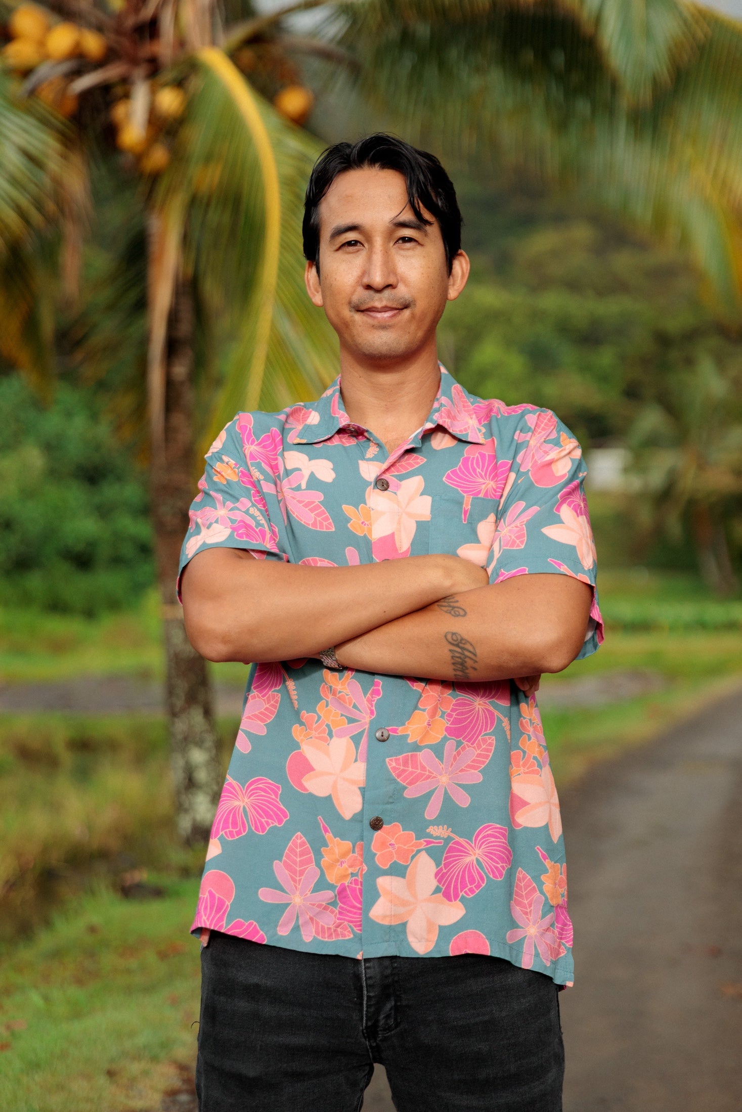 man wearing a teal aloha button up shirt with pink and orange floral pattern