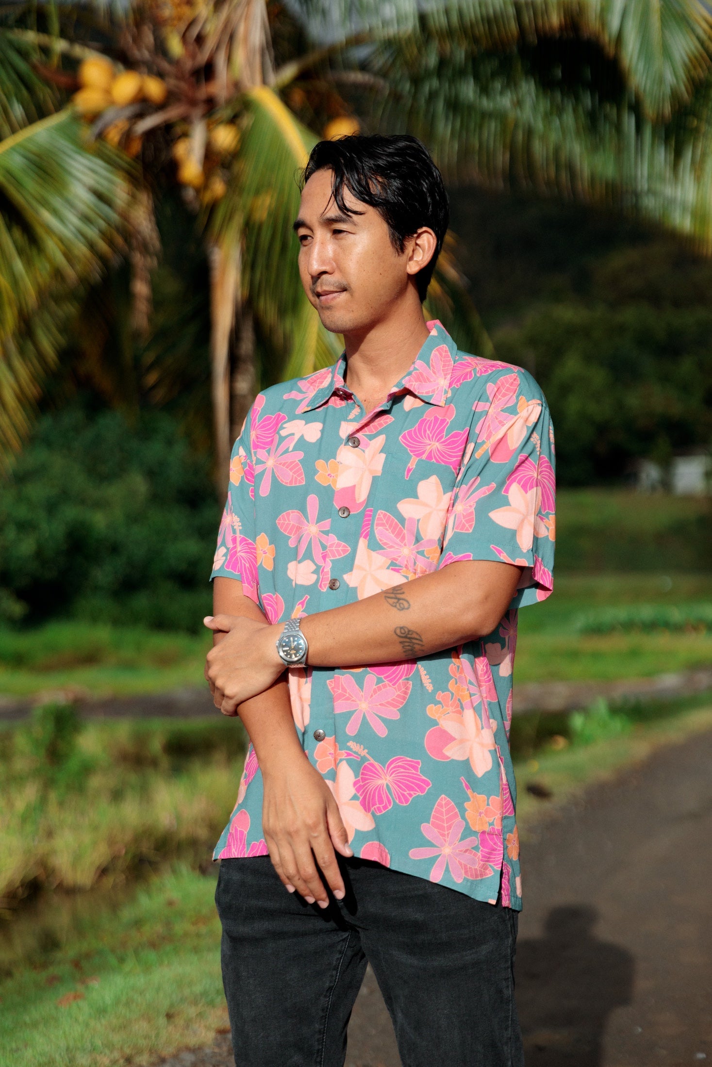 man wearing a teal aloha button up shirt with pink and orange floral pattern