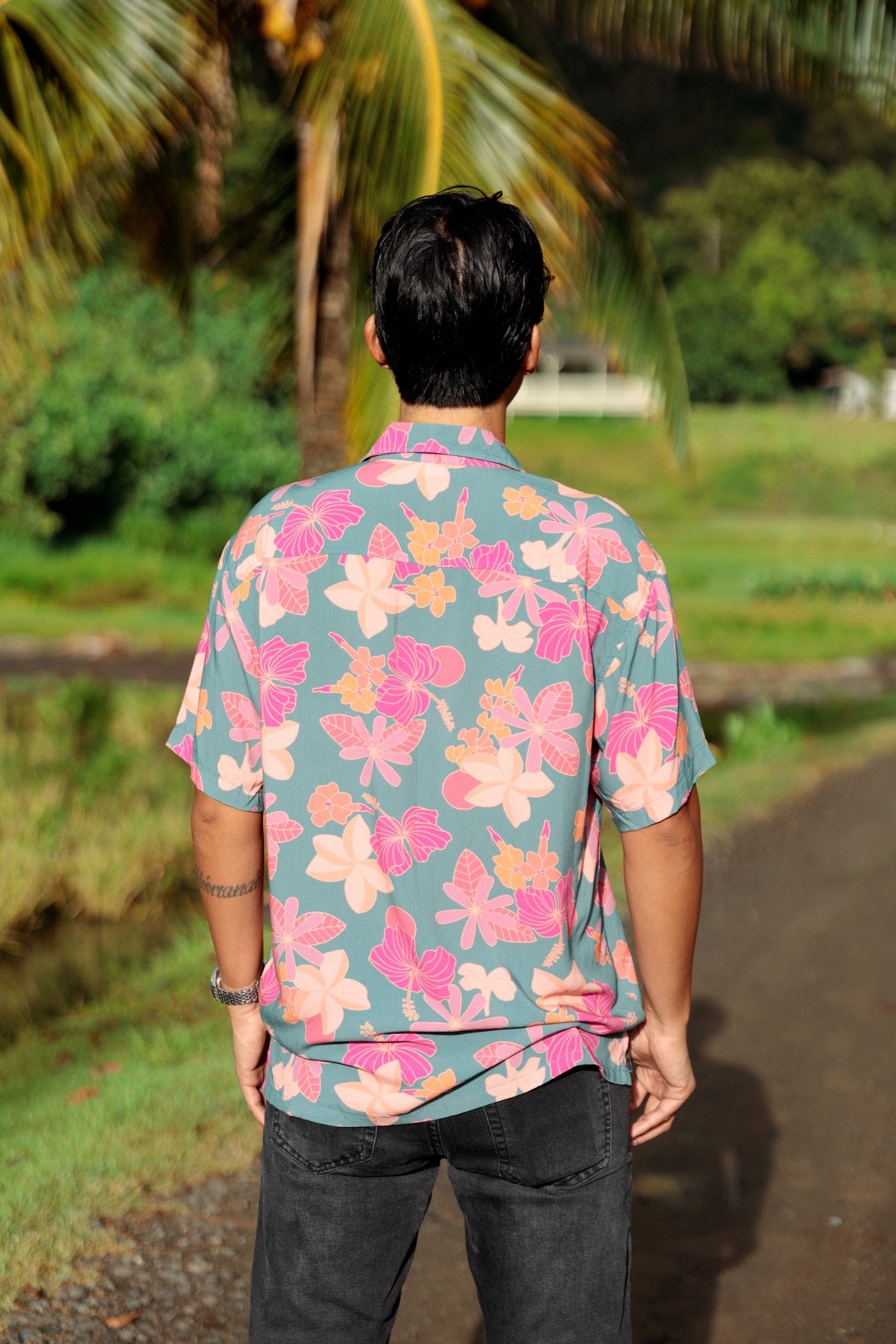 man wearing a teal aloha button up shirt with pink and orange floral pattern