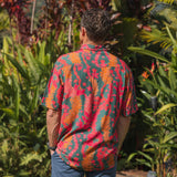man with brown hair wearing a colorful button up aloha shirt with tropical lei print