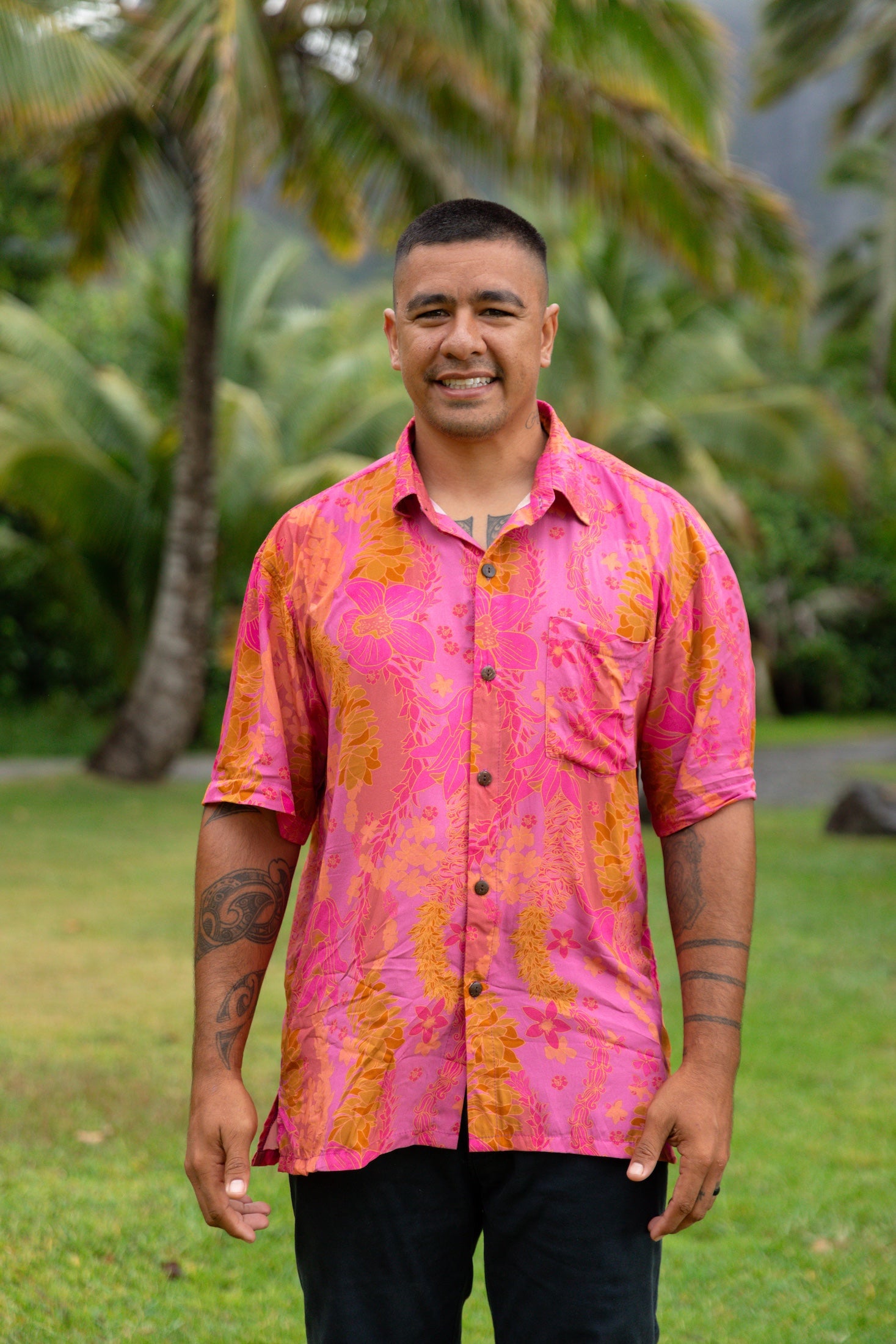 man wearing pink aloha button up shirt with lei strands