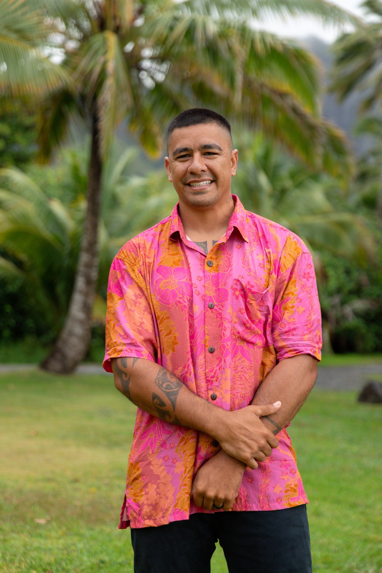 man wearing pink aloha button up shirt with lei strands