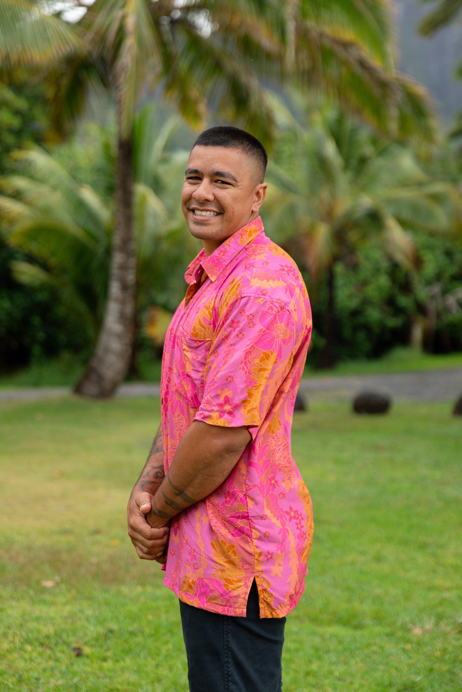 man wearing pink aloha button up shirt with lei strands