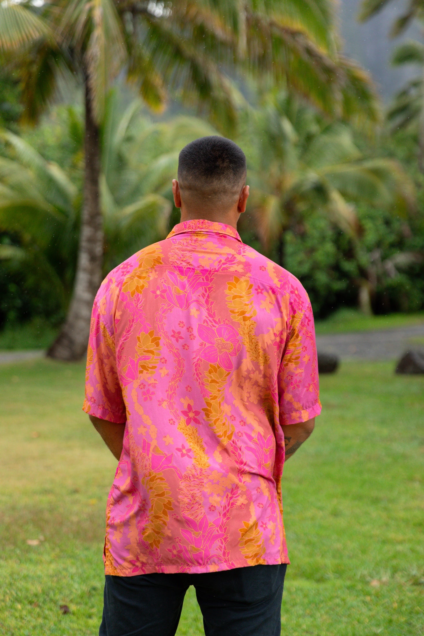 man wearing pink aloha button up shirt with lei strands