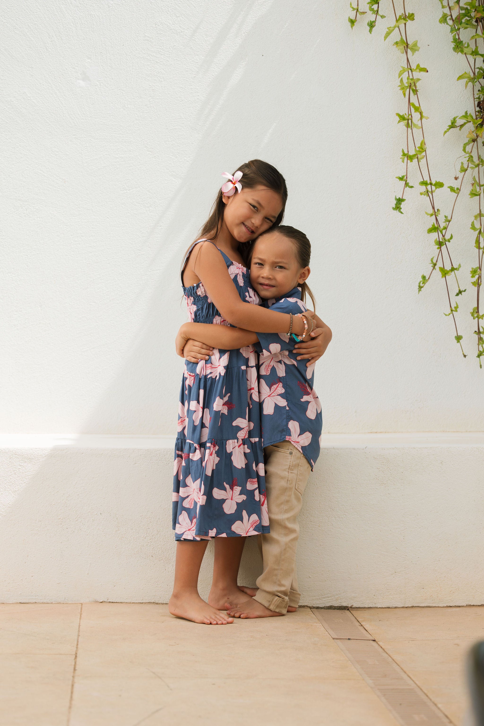 little girl wearing a tiered maxi dress in navy and pink hibiscus print.