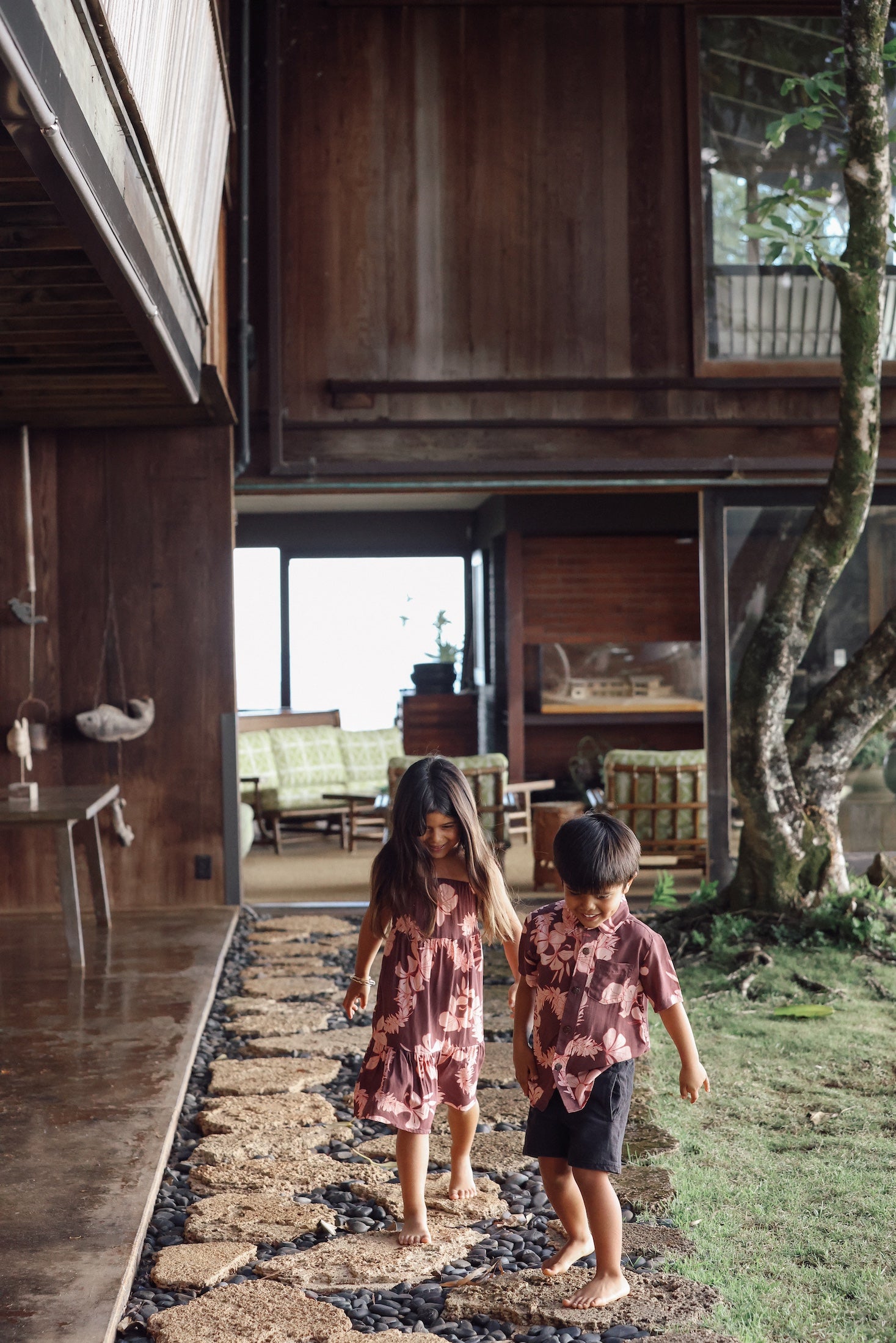 little girl  and her brother wearing matching brown outfits with light pink lei awapuhi print