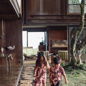 little girl  and her brother wearing matching brown outfits with light pink lei awapuhi print