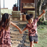 little boy wearing brown aloha shirt with pink lei awapuhi print